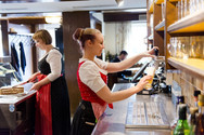 Servicekräfte in Tracht arbeiten an der Schank der Hoftaverne und zapfen Bier für die Gäste