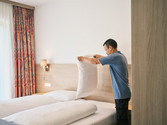 Arbeiten in der Hoftaverne Ziegelböck – Housekeeping und Zimmerpflege Mitarbeiter richtet ein Hotelzimmer der Hoftaverne Ziegelböck und bereitet das Bett vor