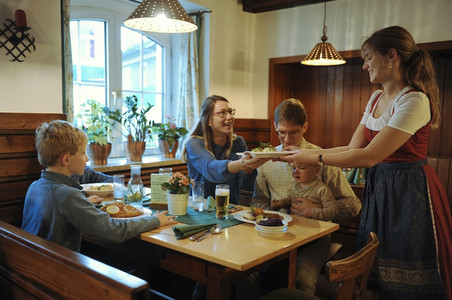 Servicemitarbeiterin serviert einer Familie mit Kindern ein Gericht im Gasthaus der Hoftaverne Ziegelböck Servicemitarbeiterin serviert einer Familie mit Kindern ein Gericht im Gasthaus der Hoftaverne Ziegelböck